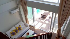 A living room with a sofa, a coffee table, and a view of an outdoor patio with a table and chairs. - Arkipelago Beach Resort (Puerto Galera)