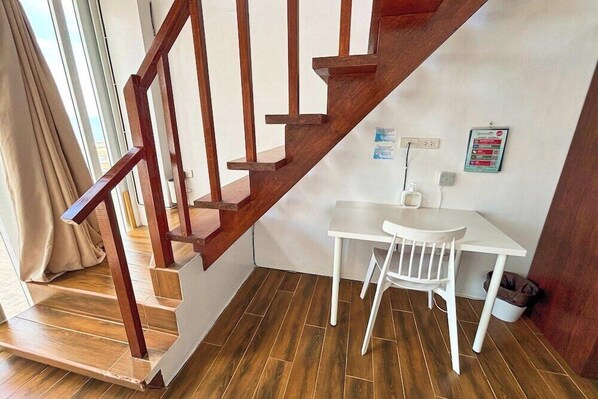 A staircase with wooden railings leading to a white table and chair, a whiteboard, and a wall-mounted power outlet. - Arkipelago Beach Resort (Puerto Galera)