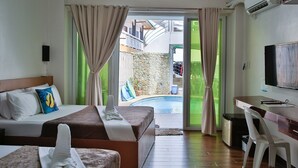 A hotel room with a bed, a desk, a TV, and a view of an outdoor swimming pool. - Arkipelago Beach Resort (Puerto Galera)