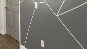 Un corridoio con una parete grigia caratterizzata da un motivo geometrico e un quadro raffigurante un elefante con vegetazione.