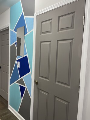 Un couloir avec un mur orné d’un motif géométrique et une porte fermée au design traditionnel.