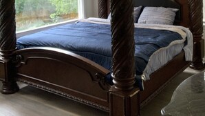 Un letto a baldacchino con una struttura in legno scuro e una coperta blu.