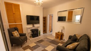 A living room with a fireplace, sofa, television, and a large mirror.
