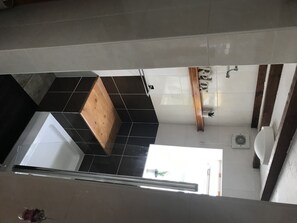 Ein modernes Badezimmer mit schwarz-weiß gefliestem Boden, einer Holzbank, einem weißen Waschbecken und einer Toilette.