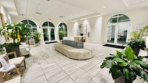 A spacious lobby with a curved seating area, multiple potted plants, and a reception desk. - FALL DEAL! 2nd FL! FREE BEACHSETUPS! CALYPSO 3-210 LOW RATES! Pool+Ocean View! (Panama City Beach)