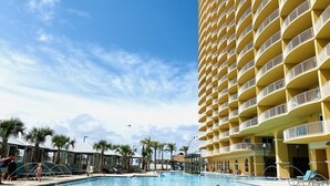 Ein Poolbereich mit einem großen Gebäude an der Seite und Palmen im Hintergrund.