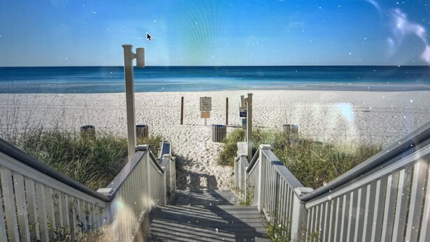 Eine Holztreppe führt zu einem Strand unter blauem Himmel.