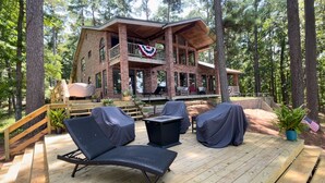 Eine zweistöckige Holzhütte mit einer Veranda, Sitzgelegenheiten im Freien und einer Flagge.