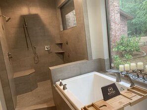 A bathroom with a bathtub, a shower, and a vanity with a mirror. There is a window with a view of greenery outside. - Eagles Point! Incredible Private Waterfront 3.5 acres. Long range water views! (Zavalla)