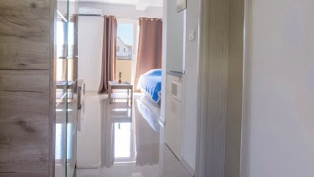 A hallway with a wooden accent wall, a glass door, and a bed with a blue cover in the background. - ♥Apartmani Kankaras | Sea View - Quiet Quarter♥ (Tivat)