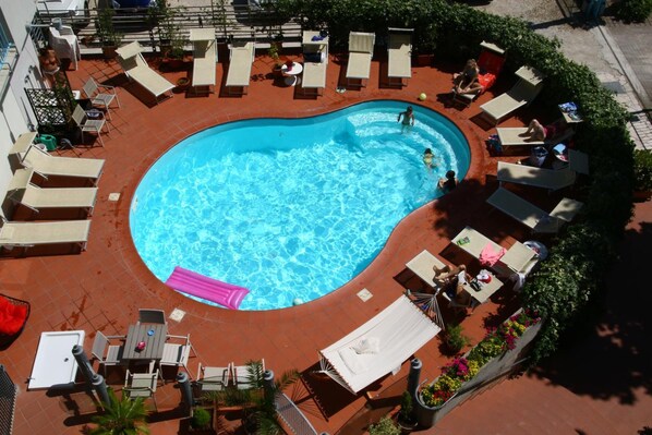 A swimming pool with lounge chairs and tables around it. - Hotel La Coccinella (Rimini)