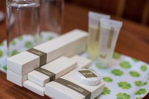 A set of toiletries including a soap bar, cotton pads, and a small bottle, arranged on a table with a patterned tablecloth. - Dechasey Villa (Siem Reap)
