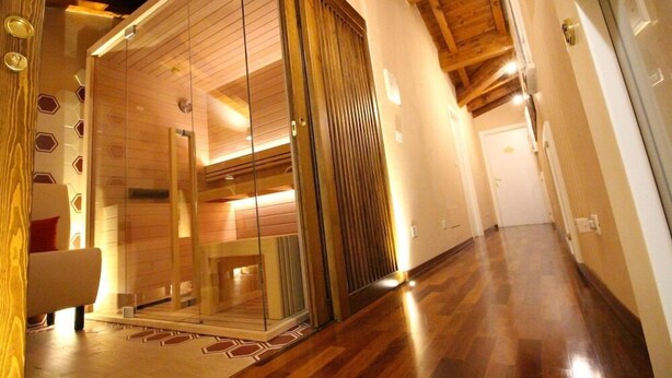 A modern interior with a wooden floor, a glass sliding door leading to a room, and a hallway with a wooden ceiling. - Casa Miramonte (Bologna)