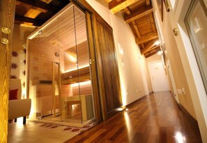 A modern interior with a wooden floor, a glass sliding door leading to a room, and a hallway with a wooden ceiling. - Casa Miramonte (Bologna)