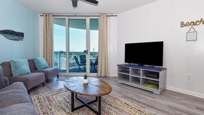 Ein Wohnzimmer mit einer Couch, einem Couchtisch, einem Fernsehschrank und einem Balkon mit Blick.