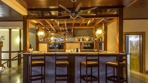 A bar area with a wooden ceiling, bar stools, and a ceiling fan. - Hotel Presidency in Electronic City (Anekal)
