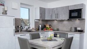 Eine moderne Küche mit grauen Schränken, einer eingebauten Mikrowelle und einem Essbereich mit Tisch und Stühlen.