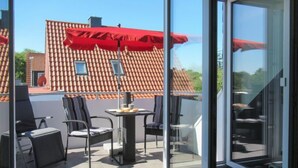 Eine moderne Terrassenausstattung mit Glastür, rotem Sonnenschirm und Tisch mit Stühlen.