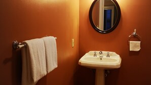 A bathroom with a sink, a mirror, and two towels hanging on a rack.