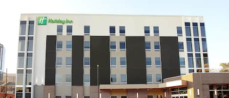 A Holiday Inn hotel with a modern facade, multiple floors, and a prominent entrance with a covered area.