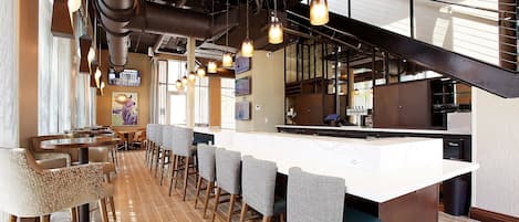 Un restaurant doté d’un long comptoir, de tabourets de bar et de luminaires suspendus.