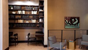 A modern library with bookshelves, seating, and a painting on the wall.