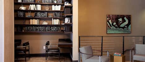 A modern library with bookshelves, seating, and a painting on the wall.