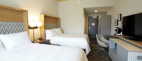 A hotel room with two beds, a desk, a chair, a television, and a desk lamp.