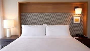 A hotel room with a bed, nightstands, a lamp, and a wall-mounted light fixture.