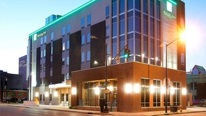 A Holiday Inn hotel with a modern design, featuring a prominent entrance with glass doors and a brick facade.
