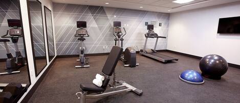 A gym with exercise equipment, a treadmill, and a large exercise ball.