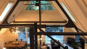Een modern interieur met een hoge plafond, dakraam, en een eethoek met een tafel en stoelen.