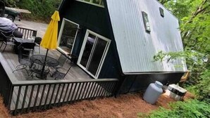 Een klein vakantiehuisje met een terras, een tafel en een gele parasol.
