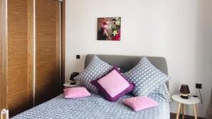 A bedroom with a bed, pillows, a bedside table, a lamp, and a wooden wardrobe. - Residence Hivernage Founty 5429 (Agadir)