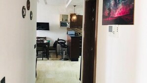A narrow hallway leading to a kitchen with a dining area, a microwave, and a painting of a galaxy on the wall. - Residence Hivernage Founty 5429 (Agadir)