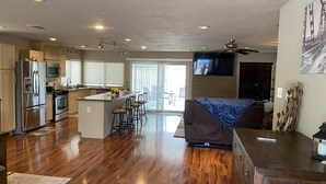 A spacious kitchen with a central island, stainless steel appliances, and a large island with bar stools. - Casa De La Roca (Albuquerque)