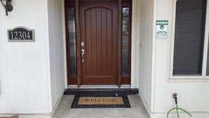 A front door with a 'WELCOME' mat, a house number sign, and a 'PARKING ONLY' sign. - Casa De La Roca (Albuquerque)