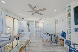 Un salón amplio con ventilador de techo, una mesa de comedor con sillas y una estantería.
