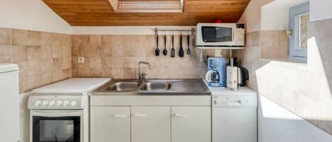 A compact kitchen with a skylight, a stove, a microwave, a coffee maker, and a dishwasher.