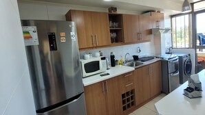 A modern kitchen with stainless steel appliances, wooden cabinets, and a large window providing natural light.