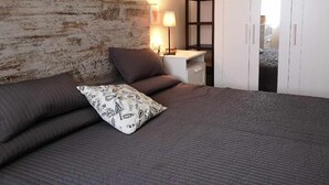Un dormitorio con cama, mesita de noche, lámpara y armario.