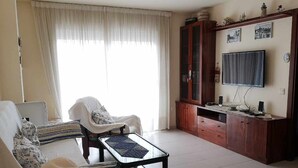Una sala de estar con sofá, sillón, mesa de centro, televisor y mueble de madera.