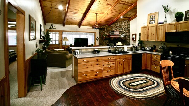 A spacious kitchen with wooden cabinets, a central island, and a stone accent wall.