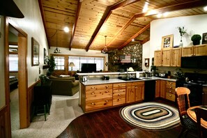 A spacious kitchen with wooden cabinets, a central island, and a stone accent wall. - Pinetop Lakes Sports Village Beautiful 3 Bed 2 Bath Condo, Golf, Ski & much more (Pinetop)