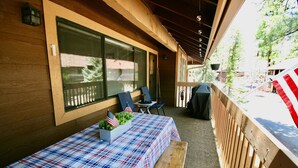 A covered patio with a table set for two, featuring a plaid tablecloth and American flags.