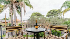 Une table ronde, deux chaises à rayures, une bouteille de champagne et deux verres posés dessus.