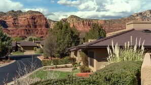 Un quartiere residenziale con case, una strada e formazioni rocciose rosse sullo sfondo.