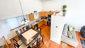 A modern kitchen with wooden cabinets, a dining area with a table and chairs, and a living area with a sofa and a small plant. - 2 Master Suites/3 King Beds/4 Bath/Mins to Airport (Colorado Springs)