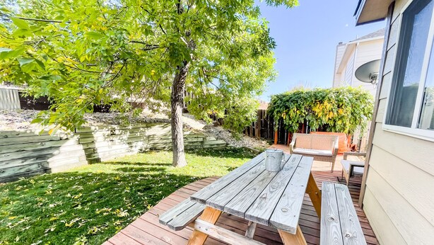 A wooden deck with a picnic table, surrounded by a grassy yard and trees. - 2 Master Suites/3 King Beds/4 Bath/Mins to Airport (Colorado Springs)