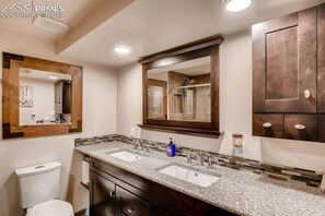 Un baño moderno con dos lavamanos, un espejo grande y una ducha.